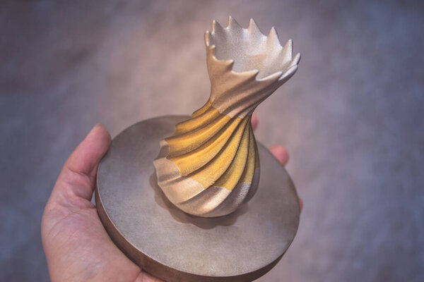 Человек держит объект, напечатанный на металлическом 3D принтере. Объект, отпечатанный в машине лазерного спекания. Современная 3D печать принтера из металлического порошка. Технология прогрессивной аддитивной печати DMLS, SLM, SLS 3d