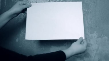 Arka plandaki kişi beyaz bir kağıt parçası tutuyor.