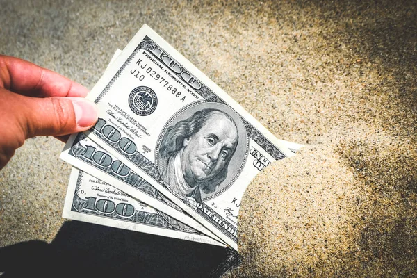 A girl takes out from the sand money notes of three hundred dollars. Concept finance money holiday relax vacation. Sunny summer warm day. A man takes out dollars from sand buried money banknotes