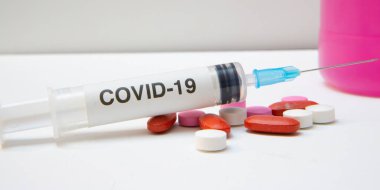 Beyaz zemin üzerinde çeşitli renk antivirüs korumalı şırınga ve tabletler