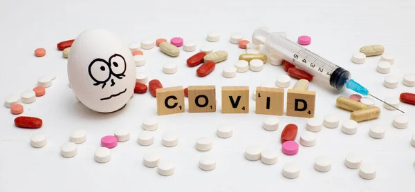 Vit Äggbottenspruta Med Inskriptionen Covid Och Olika Färgade Tabletter Bredvid — Stockfoto