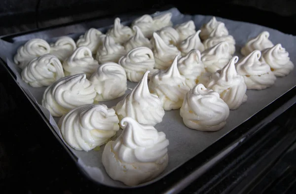 meringues cooked in the oven on a black baking tray