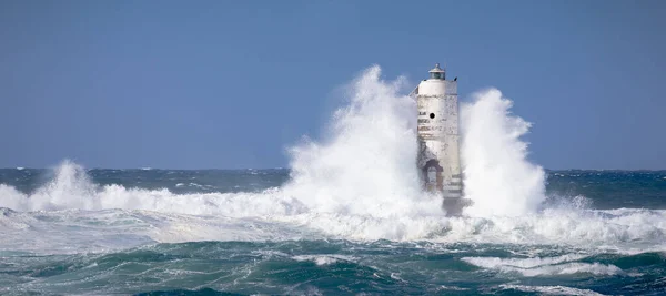 The Mangiabarche lighthouse wrapped in the waves of a mistral wind storm.The lighthouse was built over the rock from which it takes its name and located a short distance from the north-western coast of the Island of Sant'Antioco