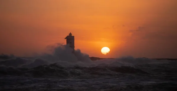 Mangiabarche deniz feneri, güzel bir gün batımında, mistral bir rüzgar fırtınasının dalgalarıyla sarmalanmış. Deniz feneri, adını aldığı kayanın üzerine inşa edilmiş ve Sant 'Antioco Adası' nın kuzey-batı kıyısından kısa bir mesafede yer almaktadır.