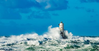 The lighthouse of the Mangiabarche shrouded by the waves of a mistral wind storm clipart
