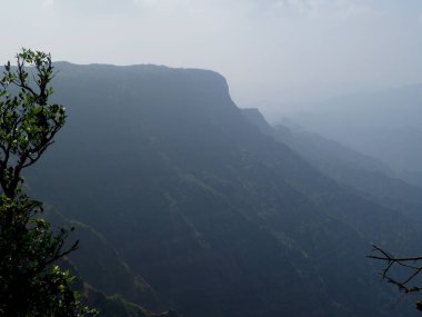 Mahabaleshwar 'daki tepelerin ve gökyüzünün puslu arka planına sahip tepe manzarası Maharashtra-Hindistan