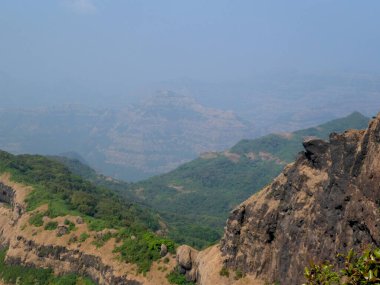 Mahabaleshwar 'daki tepelerin ve gökyüzünün puslu arka planına sahip tepe manzarası Maharashtra-Hindistan