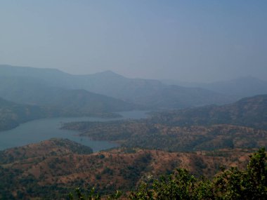 Mahabaleshwar 'daki tepelerin ve gökyüzünün sisli arka planına sahip tepe ve nehir manzarası Maharashtra-Hindistan