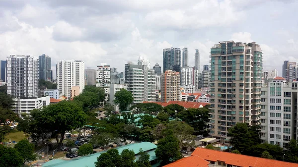 Apartman dairesi, HDB binası ve mavi gökyüzü arka planına sahip ağaçların şehir manzarası