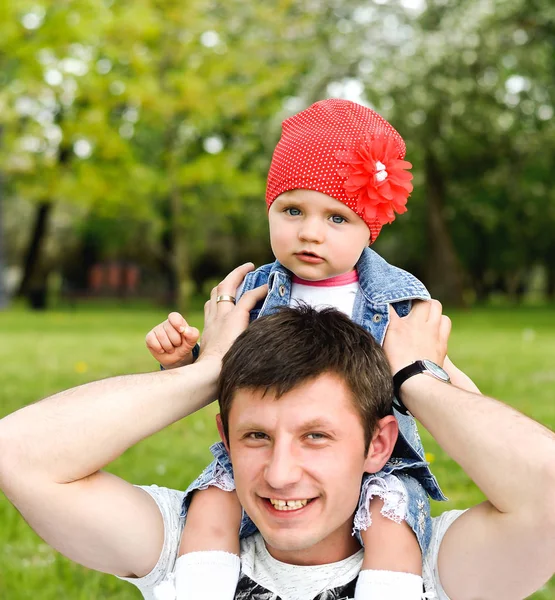 Tata trzyma jego córeczka w parku na ramionach tło zielony natura — Zdjęcie stockowe
