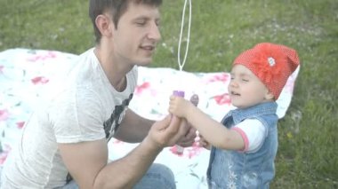 genç Baba ve kız parkta çömelme sırasında sabun köpüğü yapma