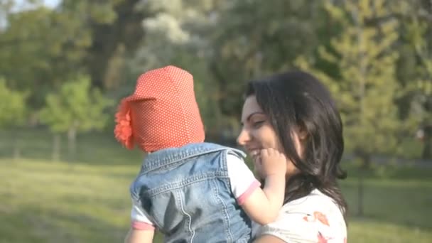 Moeder en haar kleine meisje in het park spelen en kijken naar de camera — Stockvideo