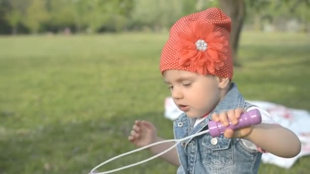 Маленька дівчинка робить мильну бульбашку в парку — стокове відео