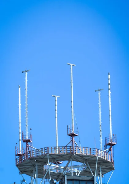 Anténa mobilního telefonu v budově proti modré obloze — Stock fotografie