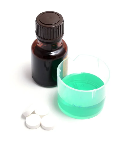 Green medical liquid in a plastic cup with bottle — Stock Photo, Image