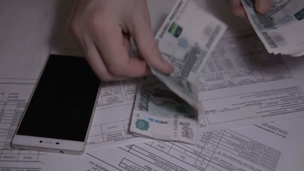Мужчина пересчитывает деньги российского рубля за белым столом на коммунальные услуги оплачивает замедленную съемку hd — стоковое видео