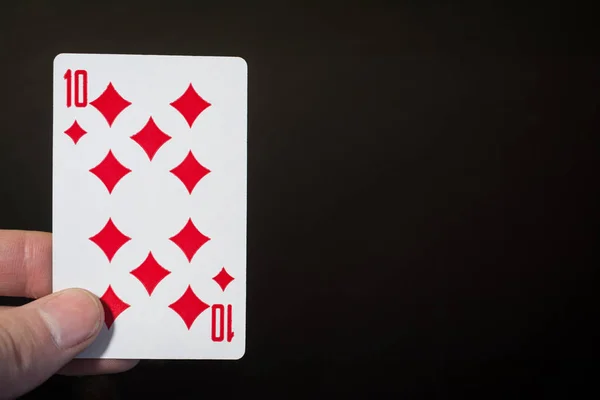 Анотація: рука людини тримає гральну картку Десять діамантів ізольовані на чорному тлі з копійкою — стокове фото