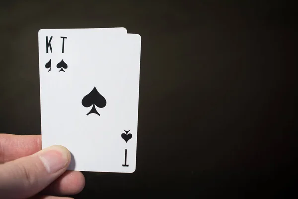 Homme main tenant carte à jouer as et sorte de pique isolé sur fond noir avec copyspace abstrait — Photo