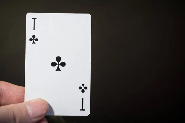 Hombre mano celebración jugando a las cartas as de clubes aislados sobre fondo negro con copyspace abstracto — Foto de Stock