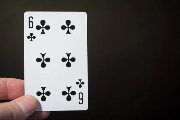 Homme main tenant des cartes à jouer six des clubs isolés sur fond noir avec copyspace abstrait copyspace — Photo