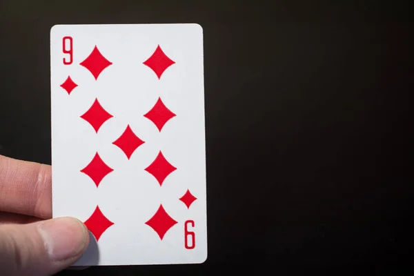Homme main tenant des cartes à jouer neuf diamants isolés sur fond noir avec copyspace abstrait — Photo