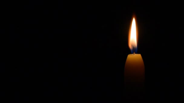 Simple burning candle on a black background, left balck copyspace — Stock Video