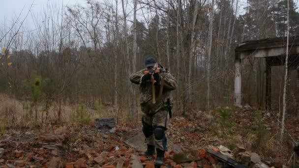 Невпізнаваний солдат лежить у лісі і прицілюється штурмовою гвинтівкою — стокове відео