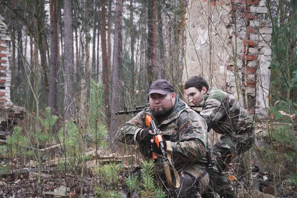 Two armed soldiers move around the destroyed building — Stockfoto