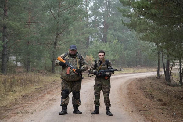 Dwóch żołnierzy z karabinem szturmowym w mundurze patrolujących teren na zewnątrz — Zdjęcie stockowe