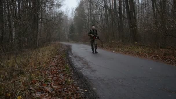 Озброєний чоловік з автоматом Калашникова і в військовому одязі — стокове відео