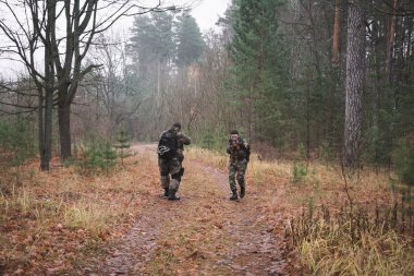 Ormanda makineli tüfekli ve kamuflajlı iki asker