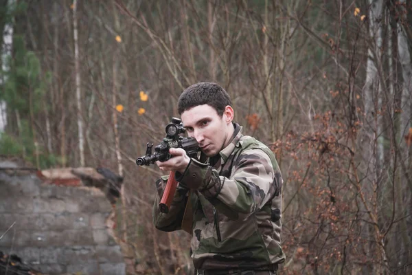 Russische soldaat met Aka-47 Kalashnikov aanvalsgeweer in camouflage gericht op een doelwit in het herfstbos — Stockfoto