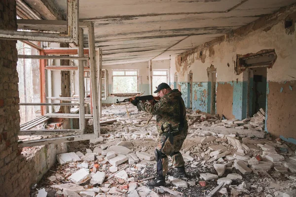 Terk edilmiş bir binada, cama silah doğrultmuş bir asker. — Stok fotoğraf
