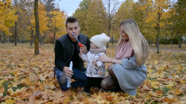 Glad familj koncept, mamma pappa och liten dotter leka med såpbubblor i höstparken — Stockvideo