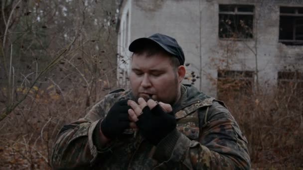 Ruský voják kouří tabákovou dýmku na pozadí opuštěné budovy — Stock video