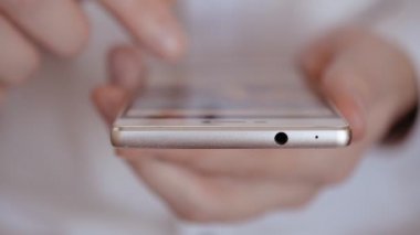 Ön açı, genç bir erkeğin cep telefonunu kaydırırken ve yazarken yakın plan görüntüsü.