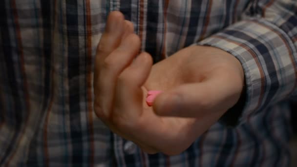 Dos píldoras antiprivativas de color rosa en una mano de hombre cerca — Vídeo de stock