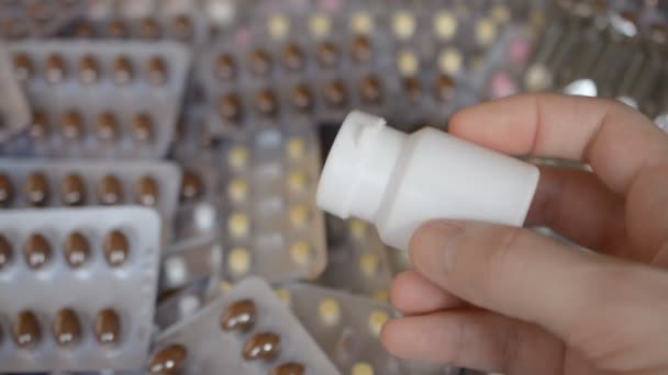 錠剤の背景に手に錠剤とホワイトボトル — ストック動画