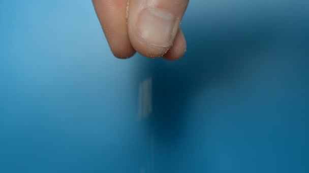 Männliche Hand, Finger salzen reichlich etwas auf blauem Hintergrund — Stockvideo