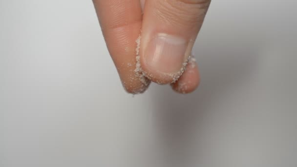 Man hand, fingrar rikligt salta något på vit bakgrund — Stockvideo