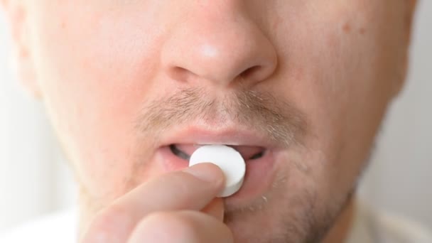 Close shot mouth of a man who eats a large white pill — Stock Video