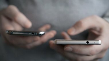 Erkek eli iki telefon tutuyor.