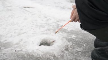 Kış Gölü 'ndeki buz çukurunda balık tutan balıkçı.
