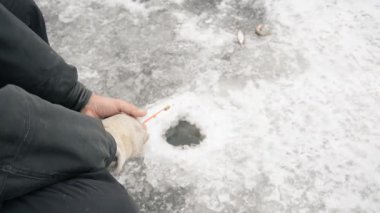 Kış Gölü 'ndeki buz çukurunda balık tutan balıkçı.