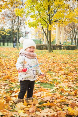 Küçük kız sonbahar günü balon değneği ve baloncuk üflerken eğleniyor.