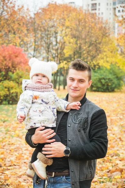 Beau papa tient dans ses bras une petite fille dans le parc d'automne — Photo