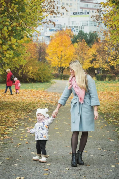 Mom care concept, Mom and little daughter are walking down the autumn street holding hands