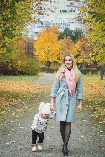 Mom care concept, Mom and little daughter are walking down the autumn street holding hands