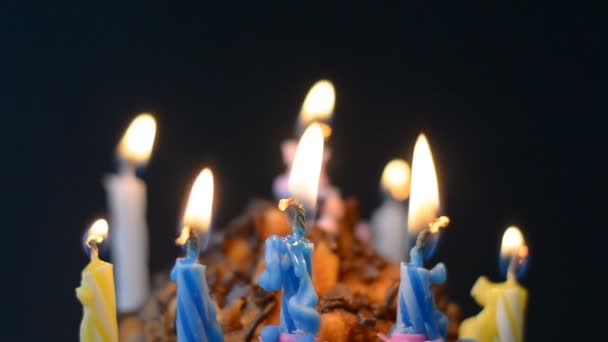 Celebração de aniversário, velas em um bolo, chama em um fundo preto — Vídeo de Stock