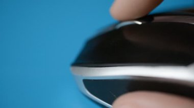Close-up of a man hand uses white wireless mouse on blue background